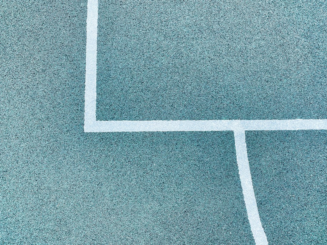 Close-up of a white pickleball court boundary line on blue surface