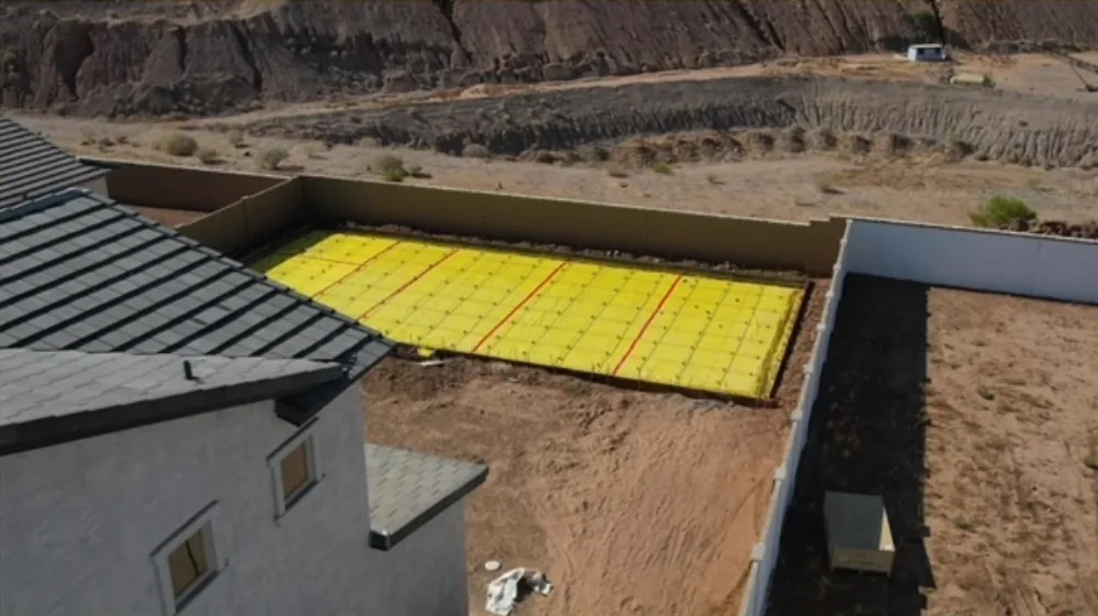 Concrete court pad formed with vapor barrier and post-tension cables in a backyard
